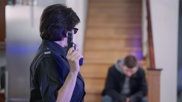 Portrait of Confident Satisfied Policewoman in Sunglasses Posing with Gun at Crime Scene with alt