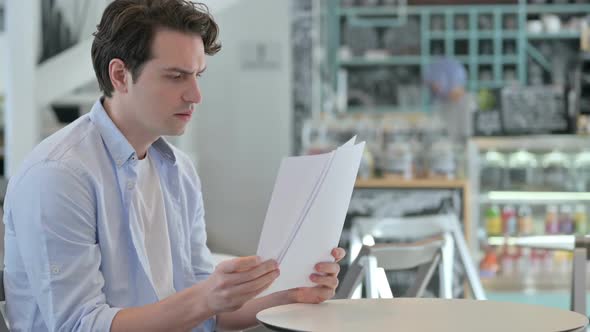Creative Man Celebrating Success While Reading Documents alt