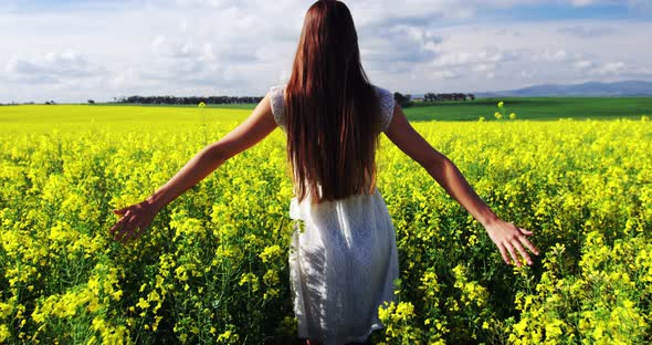 Woman touching flowers while walking in field alt