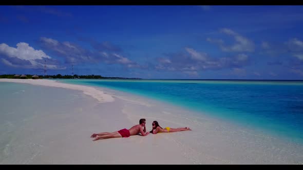 Boy and girl relax on idyllic resort beach break by blue green lagoon with white sand background of  alt
