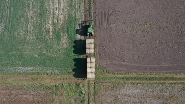 Agricultural aerial shot of a tractor driving through the fields, with an  attached carriage of larg alt