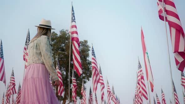 Cinematic Slow Motion of Young Stylish Woman Walking Between Many American Flags alt