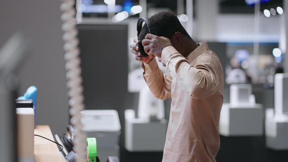 Afroamerican Guy is Testing Modern Headphones in Audio Equipment Store Medium Portrait of Male alt