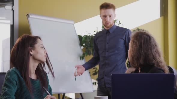 American Businessman and Two Businesswoman Sitting at Desk with Laptop. alt