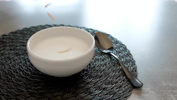 Breakfast with whole wheat cereal and corn with plum falling into the bowl. alt