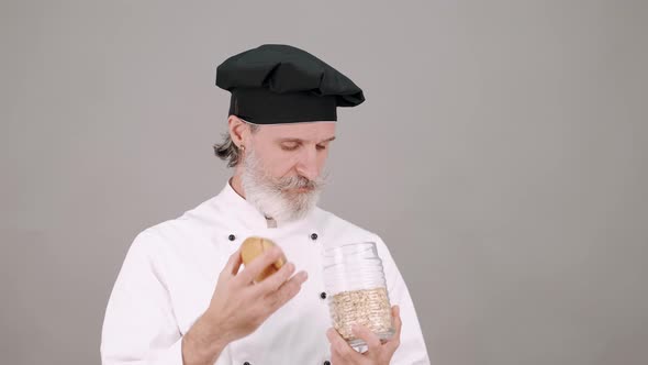 Middle Aged Chef Man Pouring Cereals on Grey Background alt