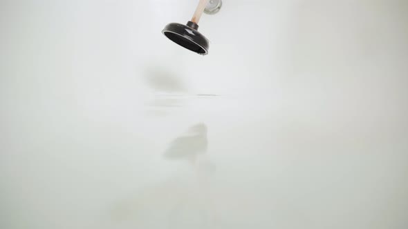 Hand Tries to Use a Plunger to Break Through the Blockage in the Bathroom with Standing Water alt