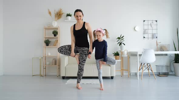 Woman with Little Daughter Doing Yoga Exercises alt