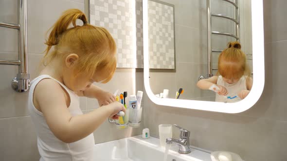 Little Girl f Brushing Her Teeth with a Toothbrush in Bathroom in the Morning