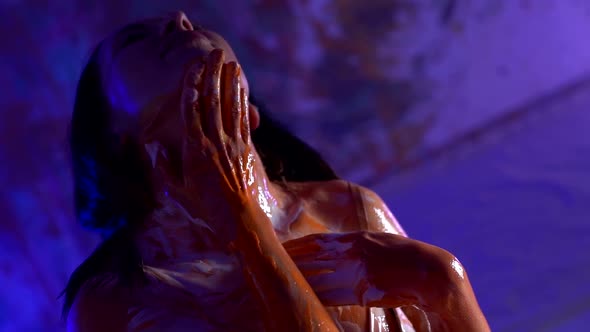 Sexy Brunette Woman Is Smearing Colors Over Her Body in Dark Room with Neon Light alt