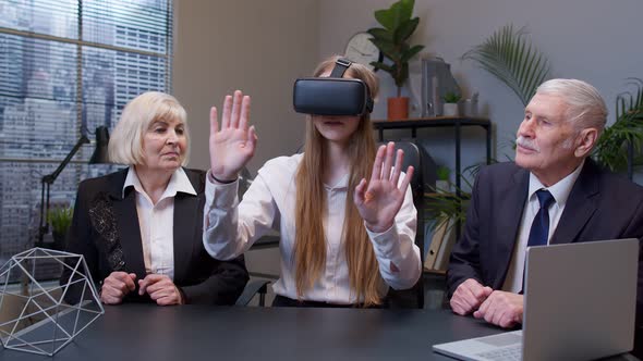 Woman Wearing Virtual Reality Glasses Tries 3D App for VR Helmet While Colleagues Supporting Her alt
