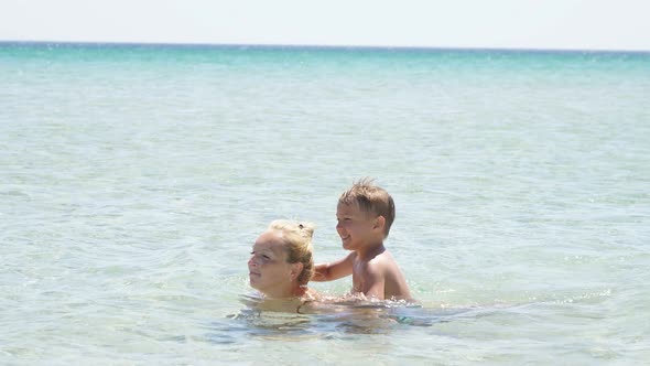 Child Happily Sat on His Mother's Back As She Swam