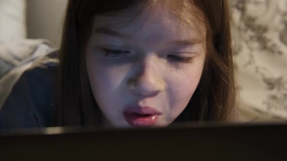 a Little Girl Uses a Laptop at Night Plays Games Watches Videos Communicates with Friends on Social