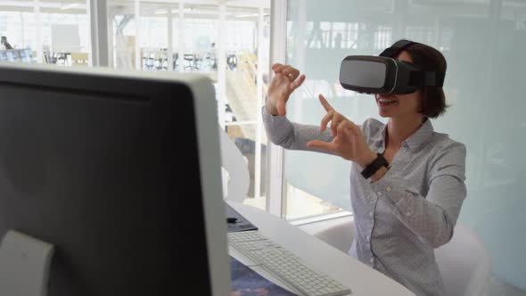 Businesswoman using virtual reality headset at desk in modern office
