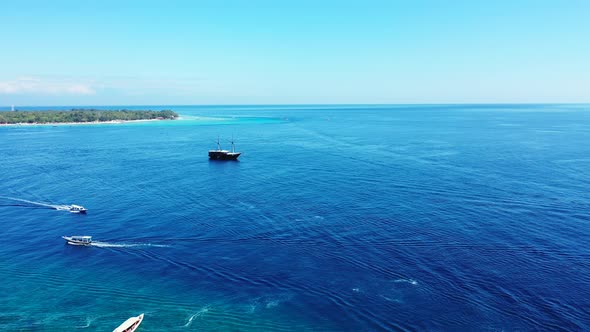 Small boats and a large ship sailing across the surface of beautiful blue waters off the coast of a alt