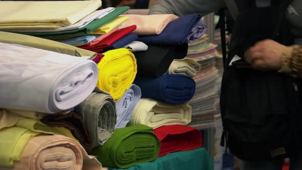 Many Colorful Clothing Rolls and Walking Customers alt