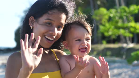 Portrait of a Joyful Mother and a Little Baby Outdoor Waving to the Camera