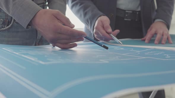 Architect and Engineer in a team discussing house drawings, closeups pointing to a drawing alt