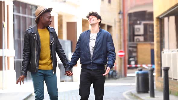 Multiracial gay couple walking embraced in London, talking and having fun tog