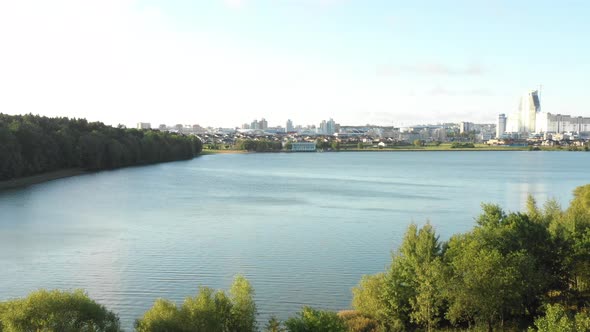 Magnificent Nature Near Urban Skyline, Drone Turning Right Above Autumn Lake and Green Forest