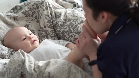 Mother Plays with Her Baby at Home on Her Lap