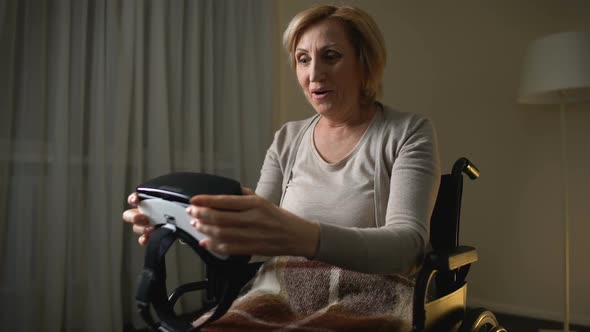 Woman in Wheelchair Holding Vr Glasses and Showing Thumbs-Up Happy and Surprised alt