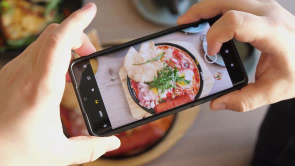 Taking Mobile Photo of Shakshuka Poached Eggs with Tomato and Bread Served in a Frying Pan
