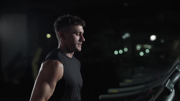 Cinematic Light Young Athletic Man Run on a Treadmill Aerobic Exercise and Endurance Training in the alt