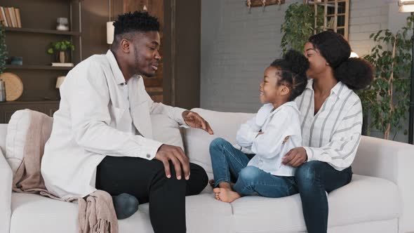 African American Family Sitting on Sofa in Living Room Chatting Casual Conversation Laugh alt
