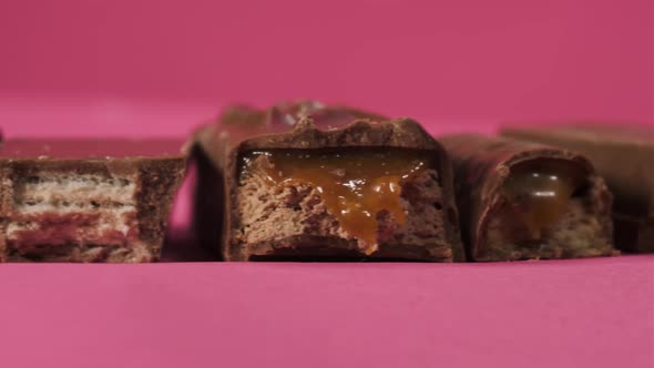 Tasty Bitten Chocolate Candy Bars Slider Move on Pink Background Isolate. Unhealthy Food for alt