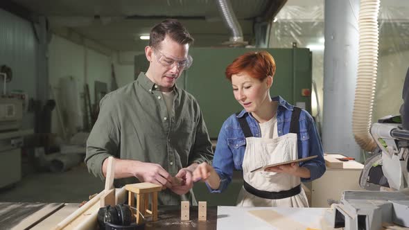 Nice Caucasian Carpenter Discussing Order Details with Customer in Workshop alt