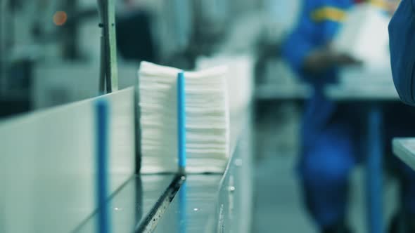 Close Up Shot of White Paper Napkins Being Placed Onto a Conveyor alt