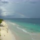 Drone establishing shot with rainbow and people enjoying beautiful tropical white sand beach resort. - VideoHive Item for Sale
