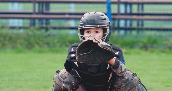 Portrait of a Boy Baseball Player on a Blurry Background, the Catcher in Protective Gear Catches a alt