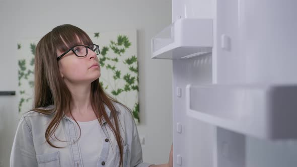 Family Budget, Young Girl Opens Doors of an Empty Refrigerator with No Food, No Product alt