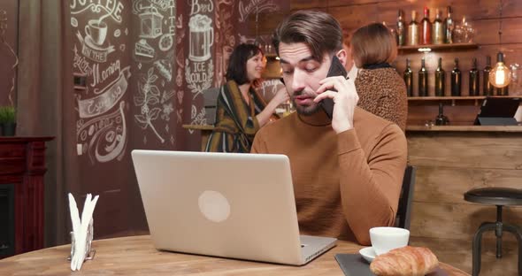 Man Engaged in a Phone Conversation in a Vintage Coffee Shop alt