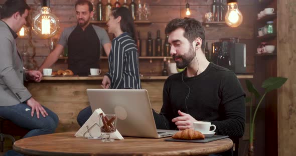 Young Freelancer Answering a Call at His Smartphone and Closes His Laptop alt