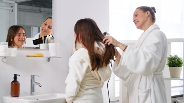 Mother and Daughter Drying Hair in Bathroom