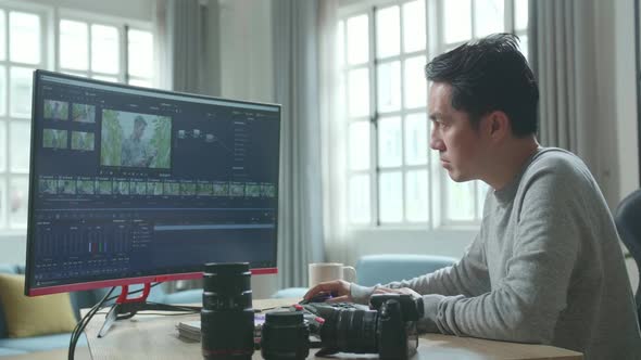 Asian Video Editor Or Colourist Man Using Desktop Computer For Editing Video While Working At Home alt