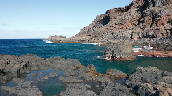 Aerial dolly over Atlantic ocean coast with volcanic relief in sunny alt