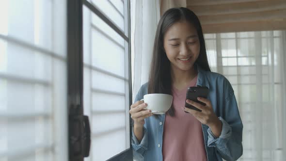 Asian woman drink coffee and typing mobile phone.