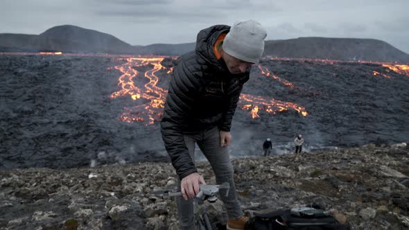 Photographer Preparing Drone In Landscape With Flowing Lava alt