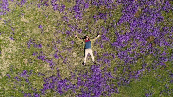 Bearded Man Lies on the Field in Violets Top-down View
