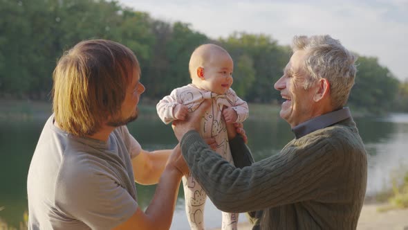 Three Generations of Men. Grandpa, Father and Little Grandson. Sunset, the Bank of the River alt