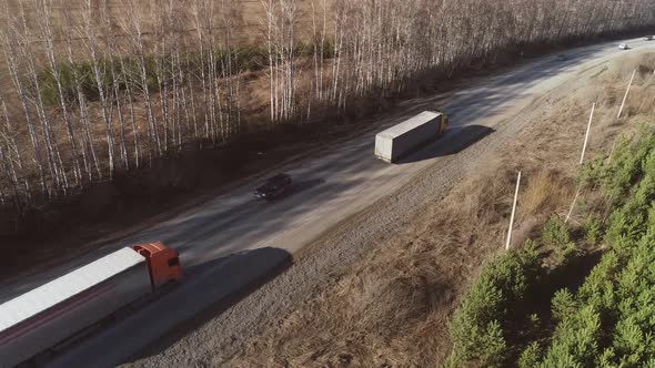 Aerial view of three trucks and cars are driving along the spring road 16 alt