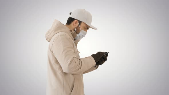 Caucasian Man in a Medical Mask Walking and Using the Phone on Gradient Background. alt