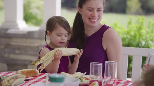 Mother and daughter enjoying dinner at backyard barbeque