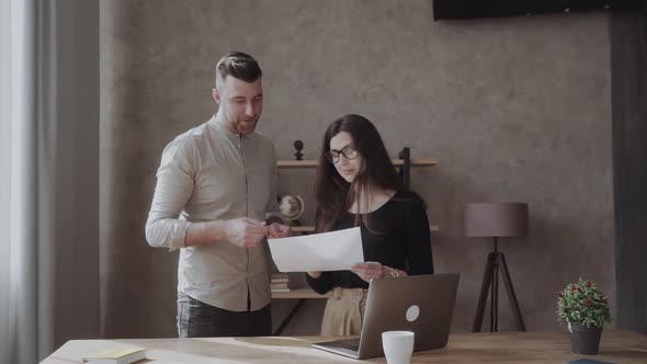 Male Coworker Showing Document with Project Results Talking To Caucasian Female Colleague alt