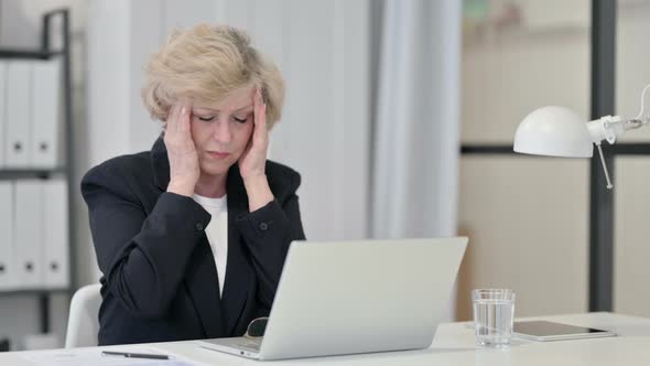Old Businesswoman Having Headache While Working on Laptop alt