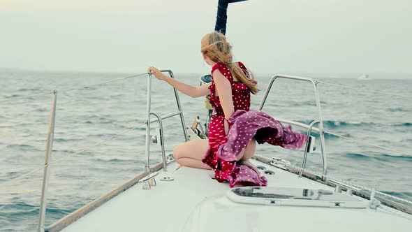 Girl in an Evening Dress Stands on a Yacht at Sunset alt
